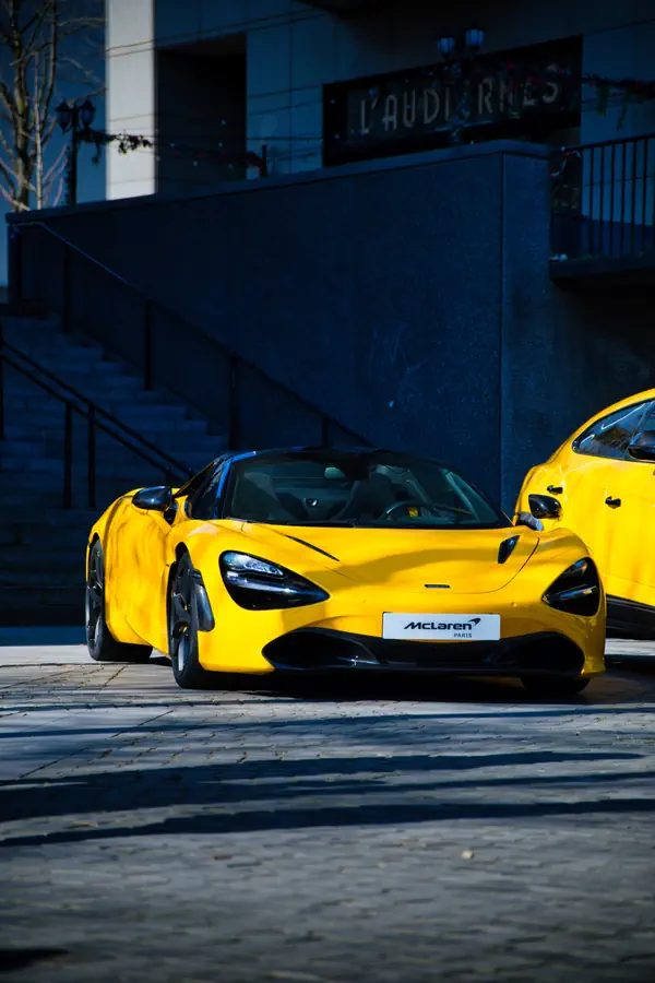 McLaren 720S jaune photographiée de trois-quarts avant, montrant son design aérodynamique distinctif avec ses phares LED caractéristiques et son splitter avant.