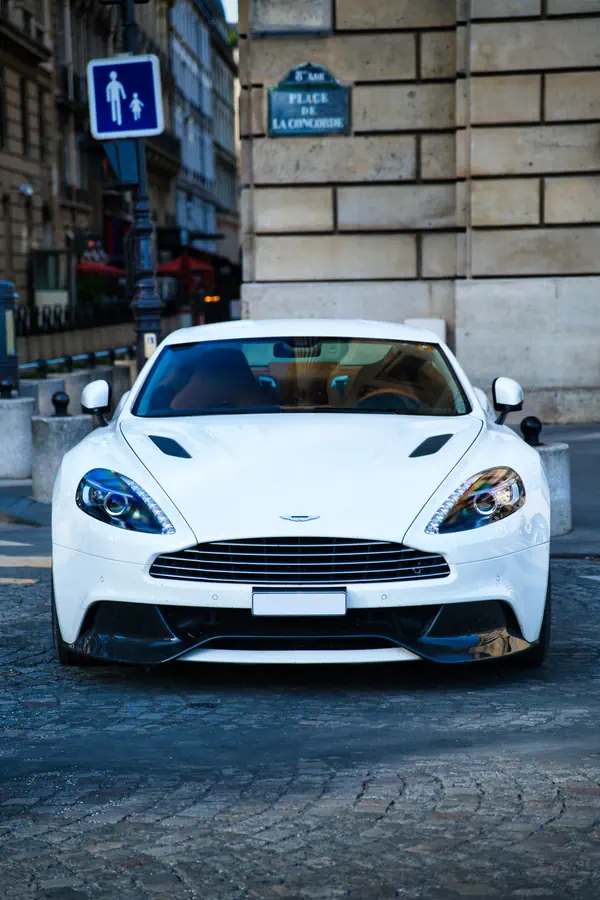 Aston Martin Vanquish blanche photographiée de face sur les pavés de la place de la Concorde à Paris.
