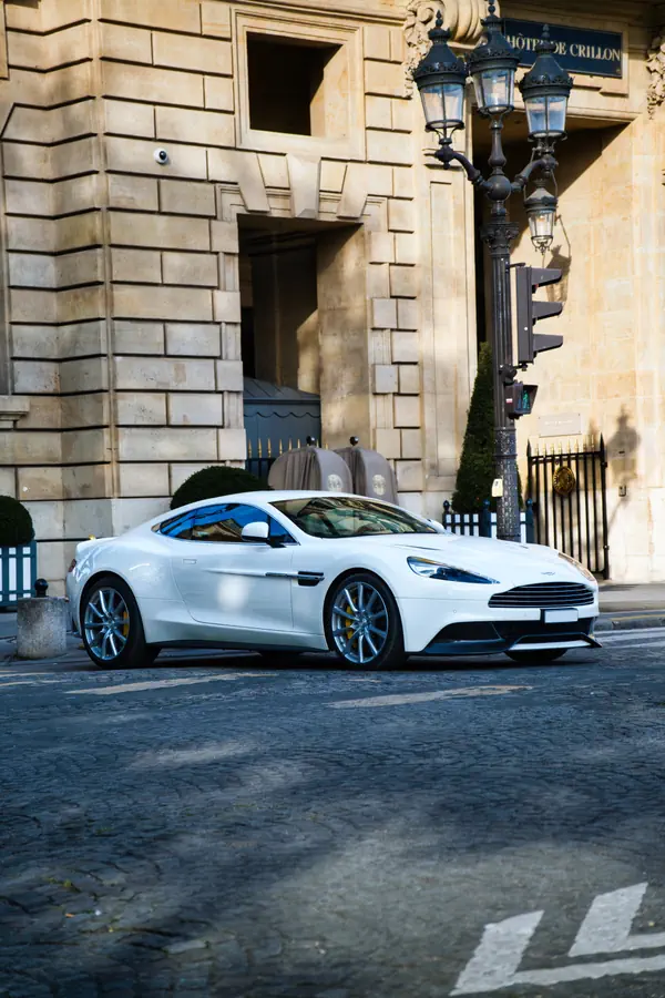 Aston Martin Vanquish blanche photographiée de trois-quarts avant devant l'Hôtel de Crillon à Paris.