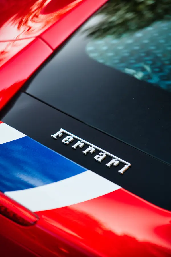 Gros plan sur le logo Ferrari en métal chromé sur le capot arrière noir d'une Ferrari 488 Pista.