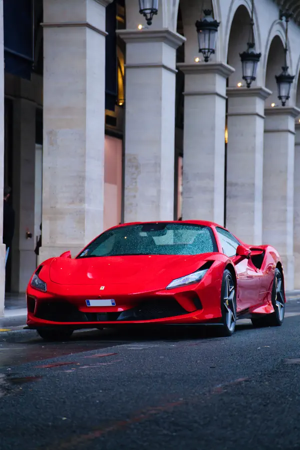 Ferrari F8 Tributo rouge éclatant photographiée devant les élégantes arcades de la Place Vendôme à Paris.