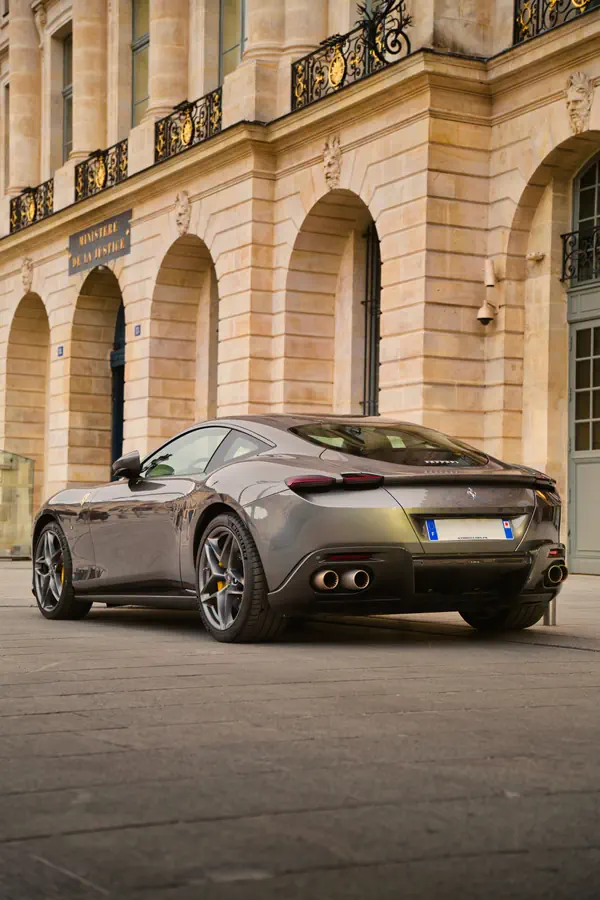 Ferrari Roma gris photographiée de trois-quarts arrière devant le Ministère de la Justice à Paris.