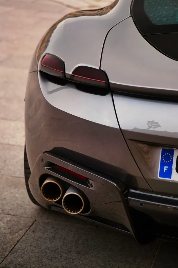 Gros plan sur l'arrière d'une Ferrari Roma gris argenté, montrant les feux arrière LED caractéristiques et les doubles sorties d'échappement circulaires.
