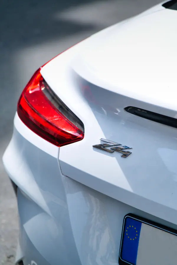 Gros plan sur l'arrière d'une BMW Z4 blanche, montrant un angle du feu arrière LED rouge et l'emblème "Z4" chromé sur le coffre.