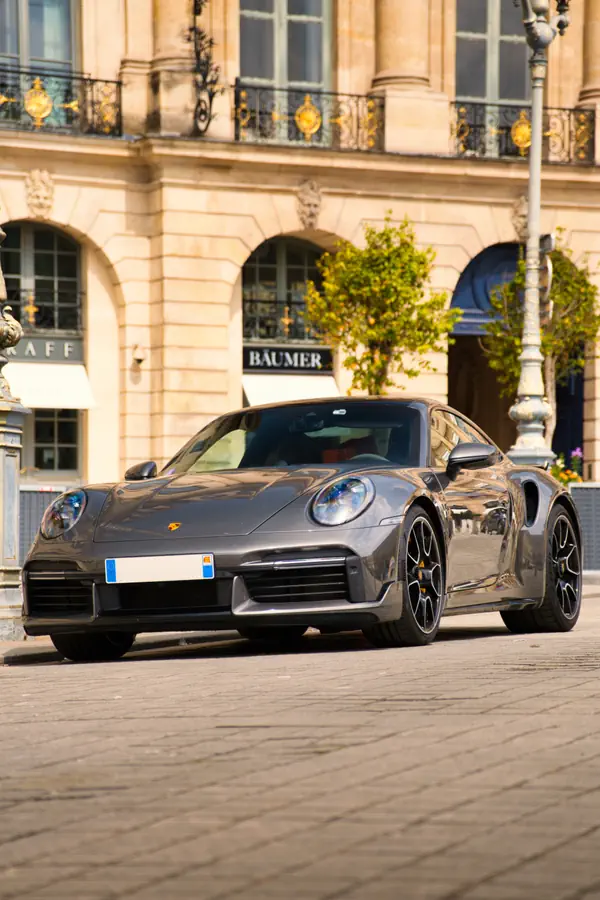 Porsche 911 Turbo gris métallisé photographiée sur les pavés de la Place Vendôme à Paris.