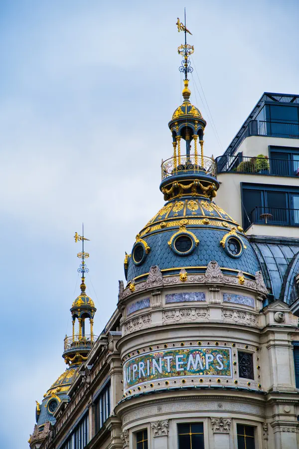 Dômes ornementés du Printemps Haussmann avec leurs toits en ardoise bleue, ornements dorés, girouettes et l'enseigne art nouveau en mosaïque colorée, symboles de l'architecture des grands magasins parisiens de la Belle Époque