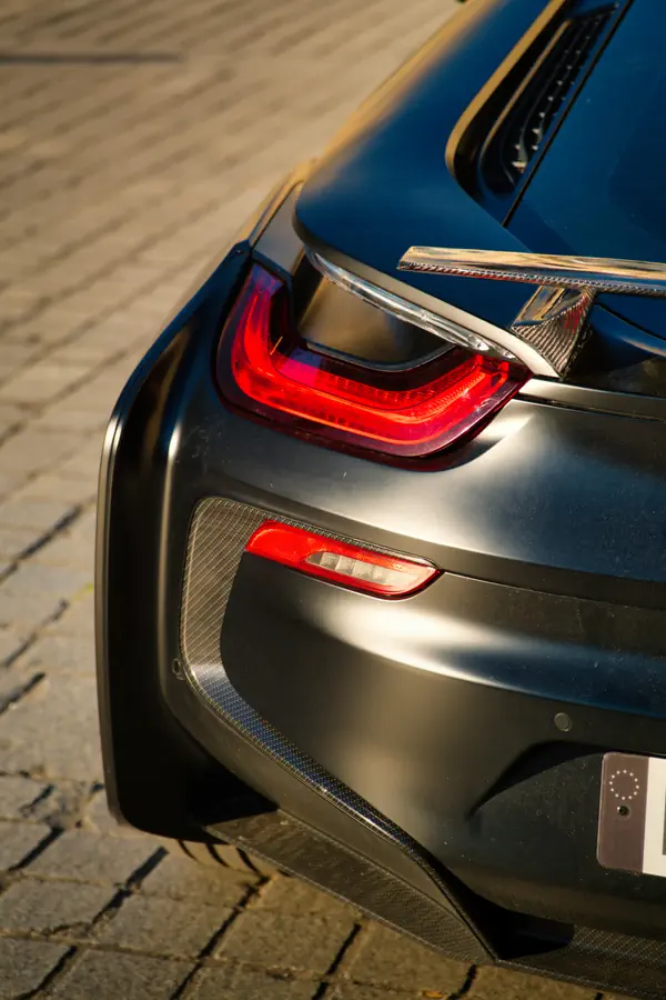 Gros plan sur le feu arrière d'une BMW i8, montrant son design futuriste avec des LED rouges intégrées dans un boîtier transparent aux lignes fluides.
