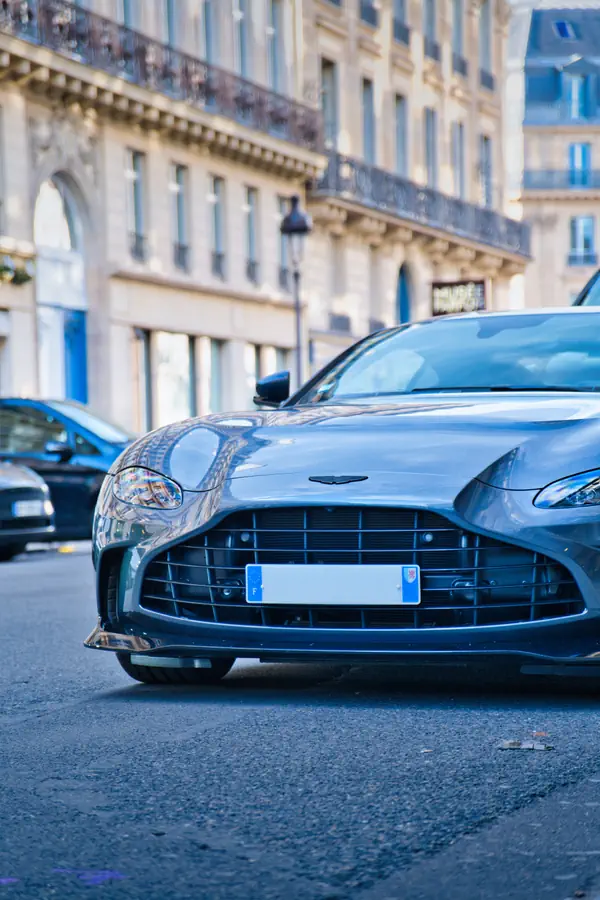 Avant d'une Aston Martin Vantage gris argenté stationnée dans une rue parisienne.