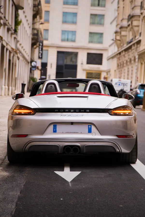 Porsche 718 Boxster S décapotable gris métallisé vue de l'arrière, garée dans une rue pavée bordée d'immeubles haussmanniens aux façades beiges avec balcons en fer forgéRéessayerClaude peut faire des erreurs. Assurez-vous de vérifier ses réponses.
