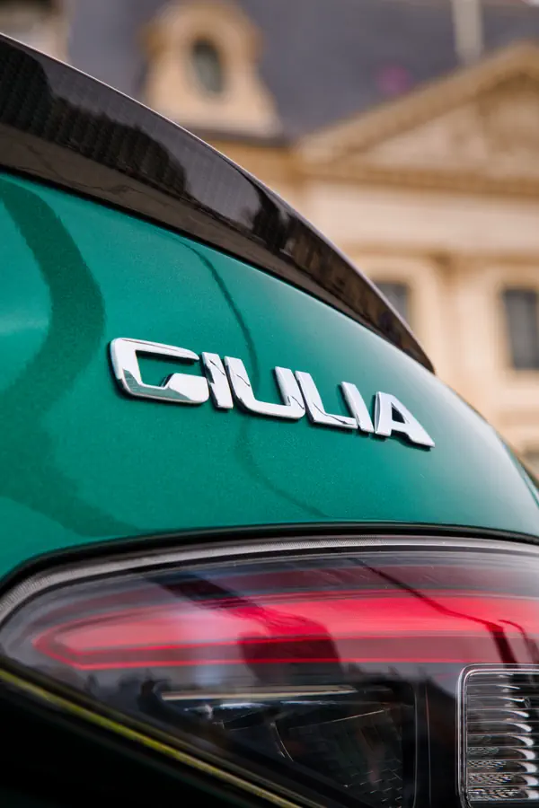 Logo Giulia en lettres chromées sur le hayon d'une Alfa Romeo vert menthe.