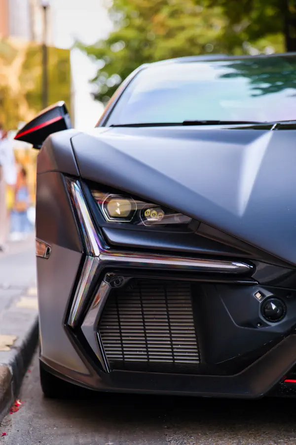 Gros plan sur le phare au design complexe d'une Lamborghini Revuelto de couleur noir mat, mettant en évidence les formes anguleuses de sa carrosserie.