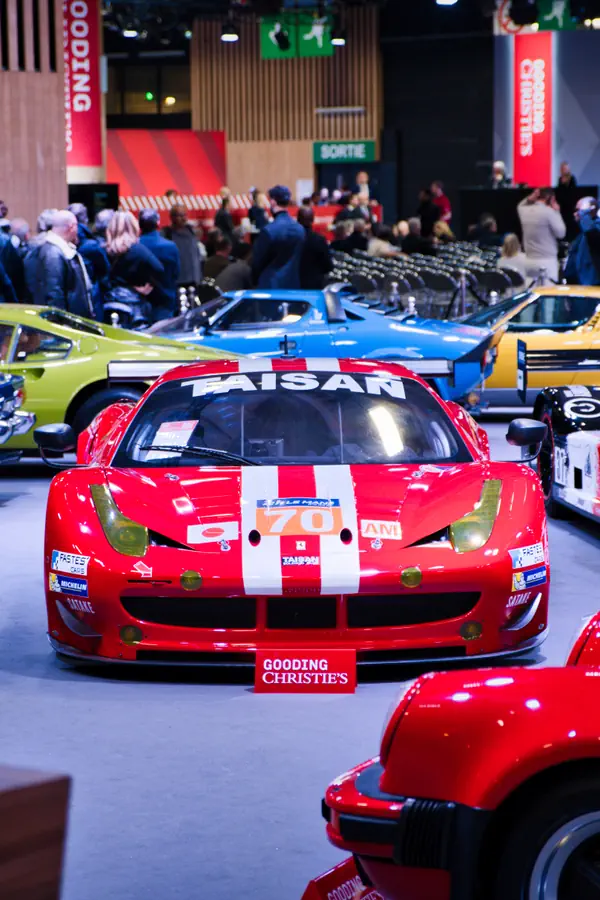 Ferrari 458 de course rouge exposée lors d'une vente aux enchères Gooding & Company dans un hall spacieux.