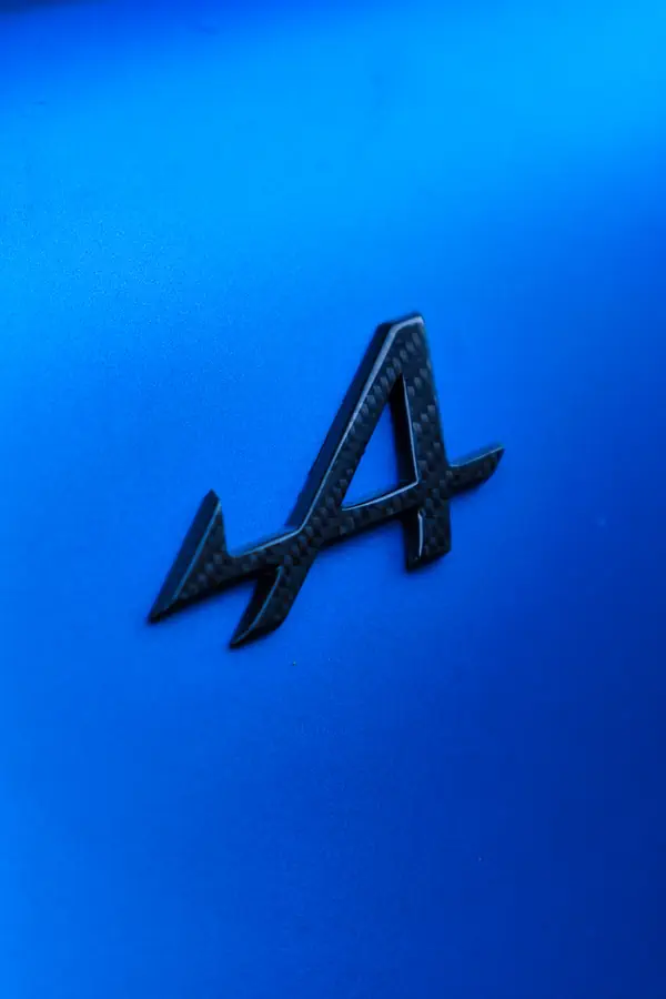 Logo Alpine en fibre de carbone photographié sur la carrosserie bleue de l'A110.