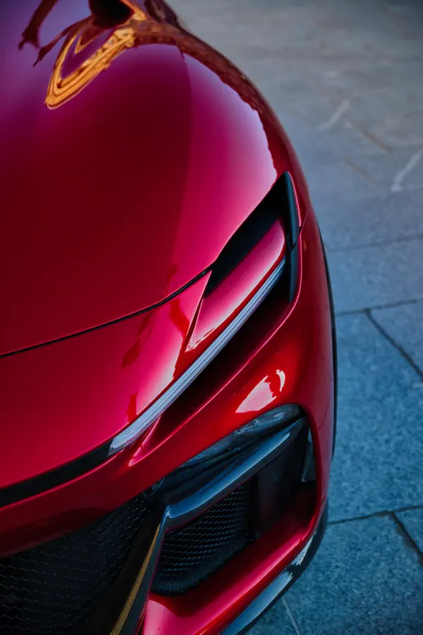 Gros plan sur le capot avant de la Ferrari Purosangue, mettant en valeur les lignes aérodynamiques sculptées dans la carrosserie rouge brillante.