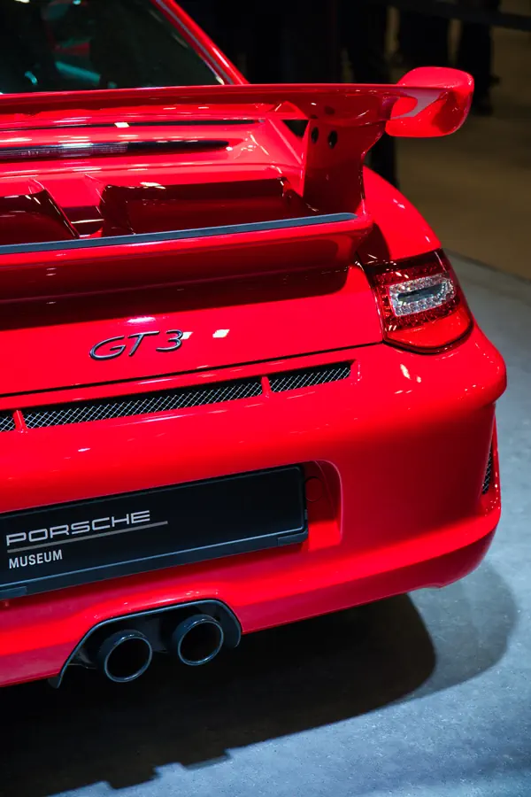 Arrière d'une Porsche 911 GT3 rouge, montrant son aileron caractéristique, ses doubles sorties d'échappement, et le badge "GT3".