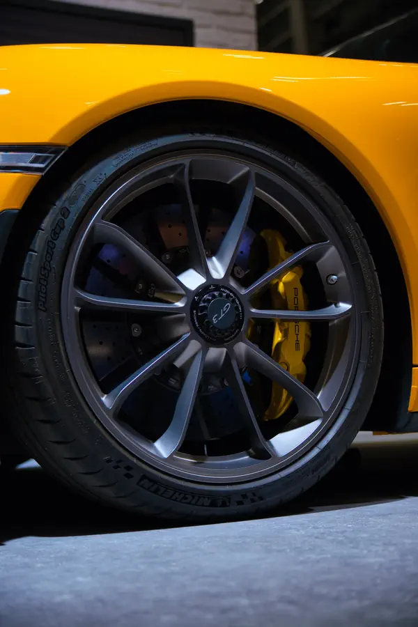 Gros plan sur la roue de la Porsche 911 GT3 jaune, montrant sa jante en alliage gris anthracite à dix branches et l'étrier de frein jaune assorti à la carrosserie.