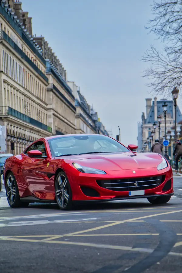 Ferrari Portofino rouge photographiée dans une rue parisienne, avec en arrière-plan des immeubles haussmanniens caractéristiques.