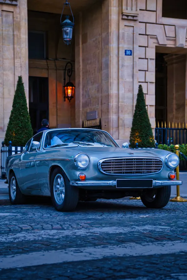 Volvo P1800 bleu clair photographiée devant une entrée d'immeuble parisien