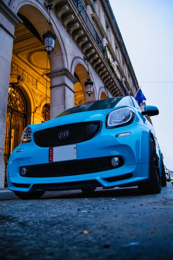 Avant de la Smart Brabus bleue photographiée en contre-plongée, montrant sa calandre noire spécifique avec le logo Brabus, son bouclier avant sportif et ses phares LED.