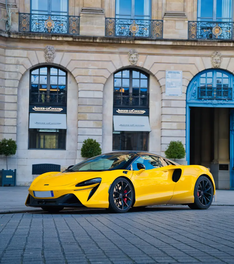 McLaren Artura jaune photographiée devant la boutique Jaeger-LeCoultre dans un bâtiment haussmannien.